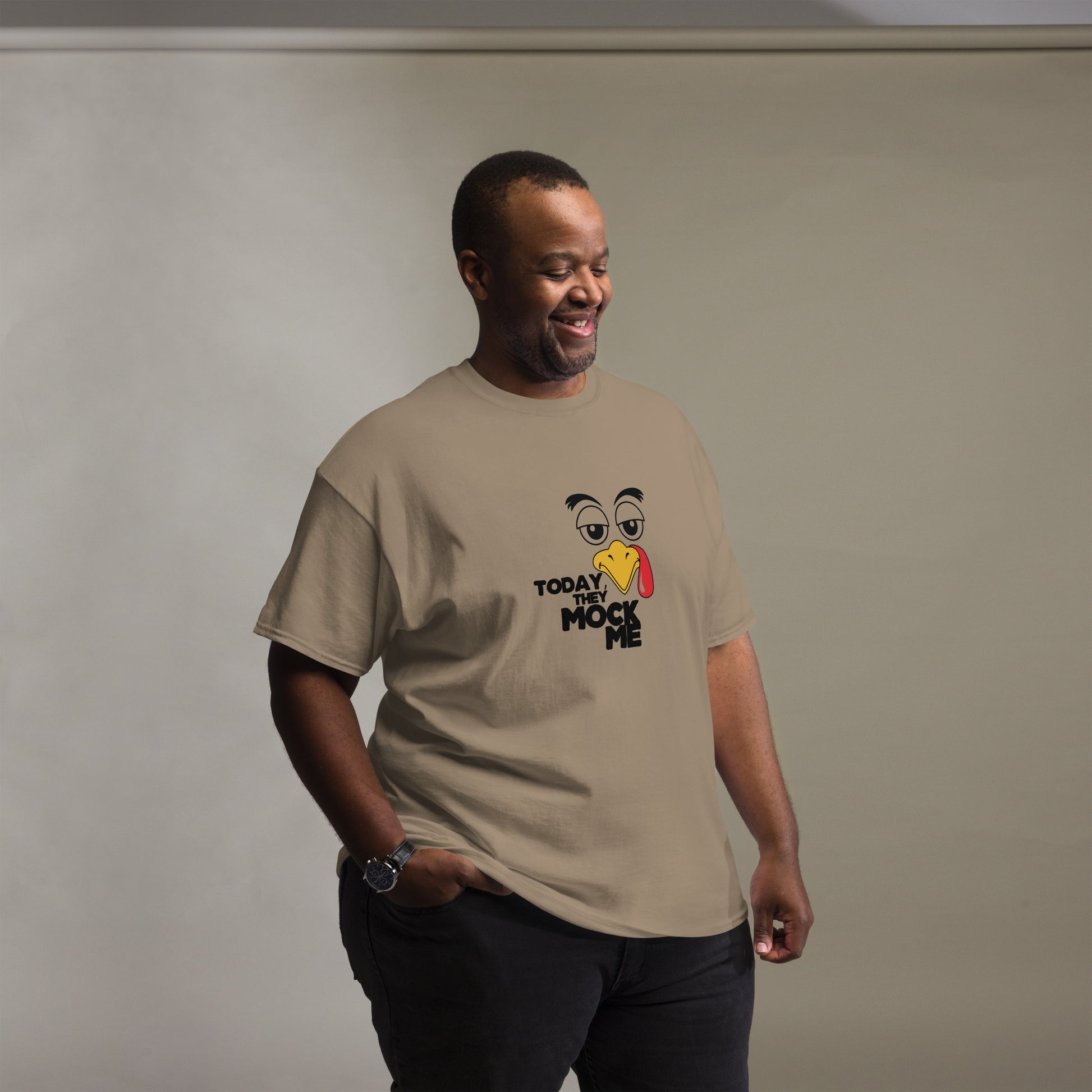 Black t-shirt with a humorous graphic of a mocking bird and the phrase 'Today They Mock Me' in bold white text. The bird has an expressive face with its tongue out, adding a playful and comedic touch to the design.