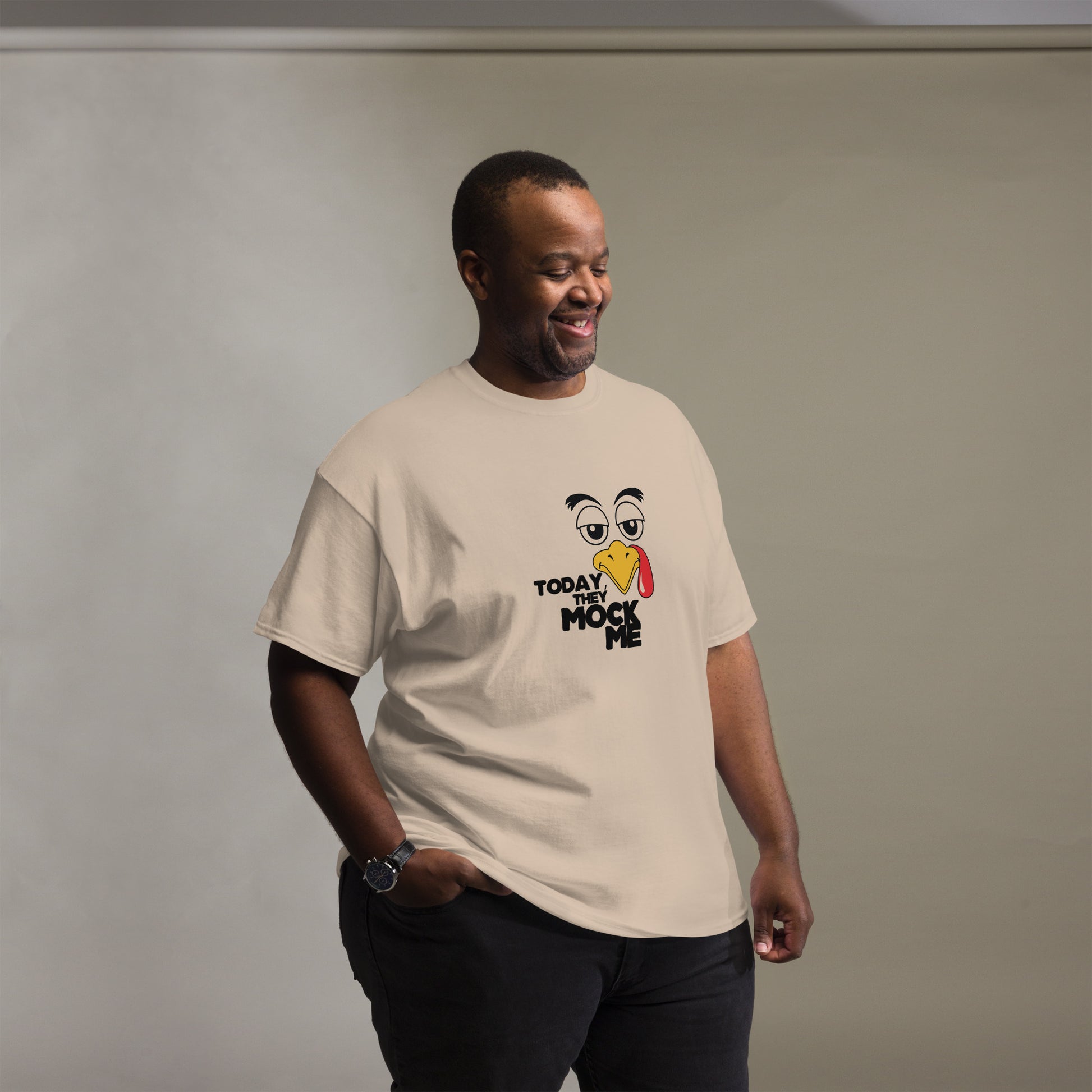 Black t-shirt with a humorous graphic of a mocking bird and the phrase 'Today They Mock Me' in bold white text. The bird has an expressive face with its tongue out, adding a playful and comedic touch to the design.