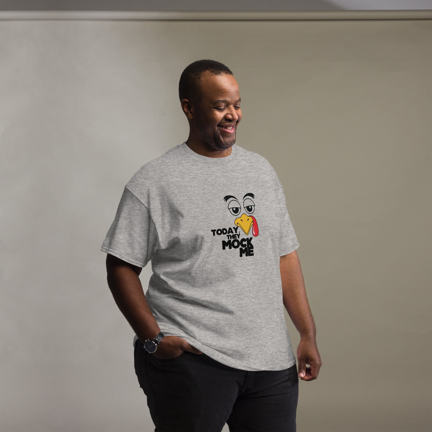 Black t-shirt with a humorous graphic of a mocking bird and the phrase 'Today They Mock Me' in bold white text. The bird has an expressive face with its tongue out, adding a playful and comedic touch to the design.